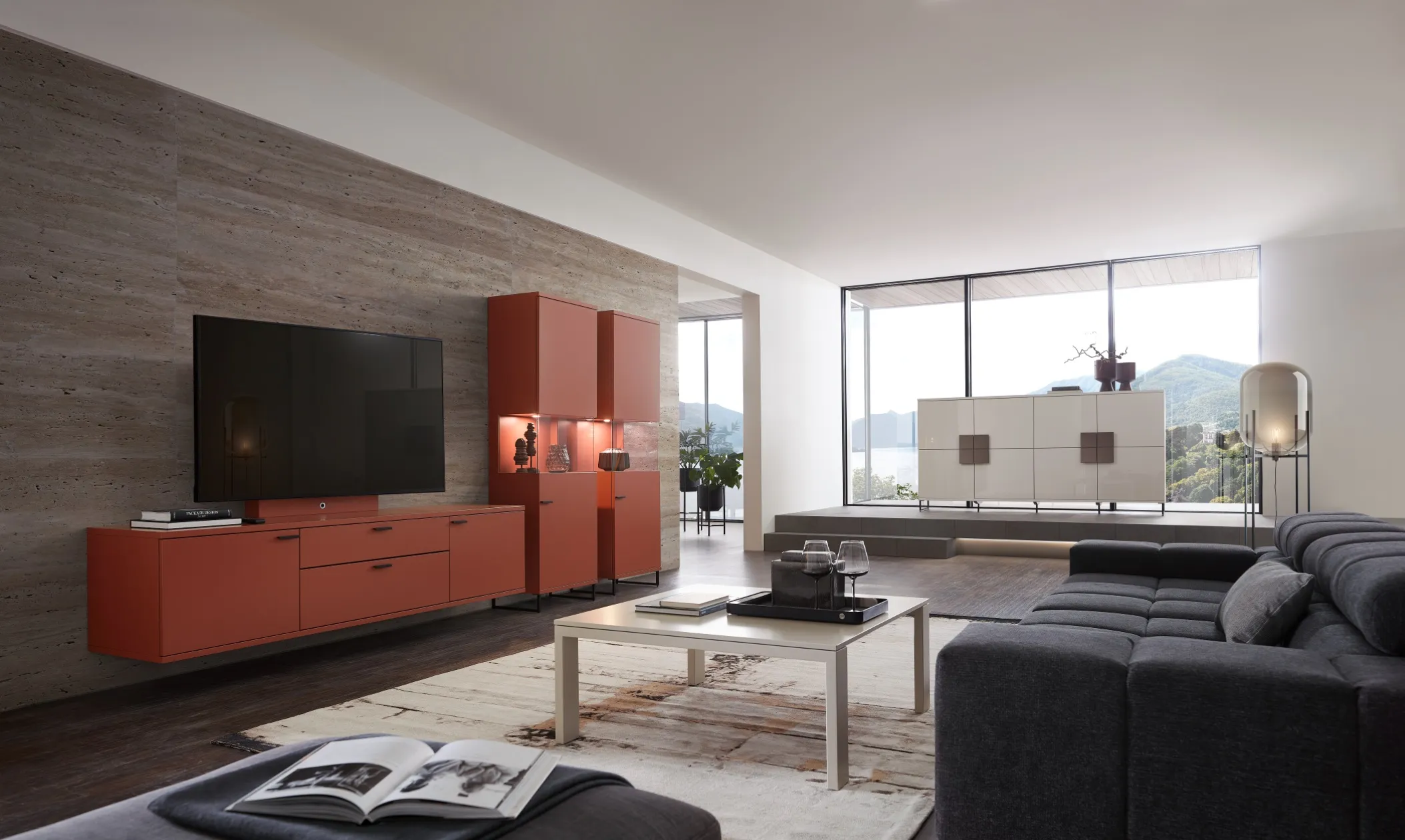 Sie sehen eine Wohnwand in rot mit hängendem Lowboard und beleuchteten Vitrinen im Wohnzimmer. Im Hintergrund passende helle Kommoden